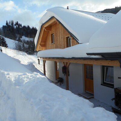 Der schneebedeckte Bauernhof mit Holzfassade und Balkon im Winter.
