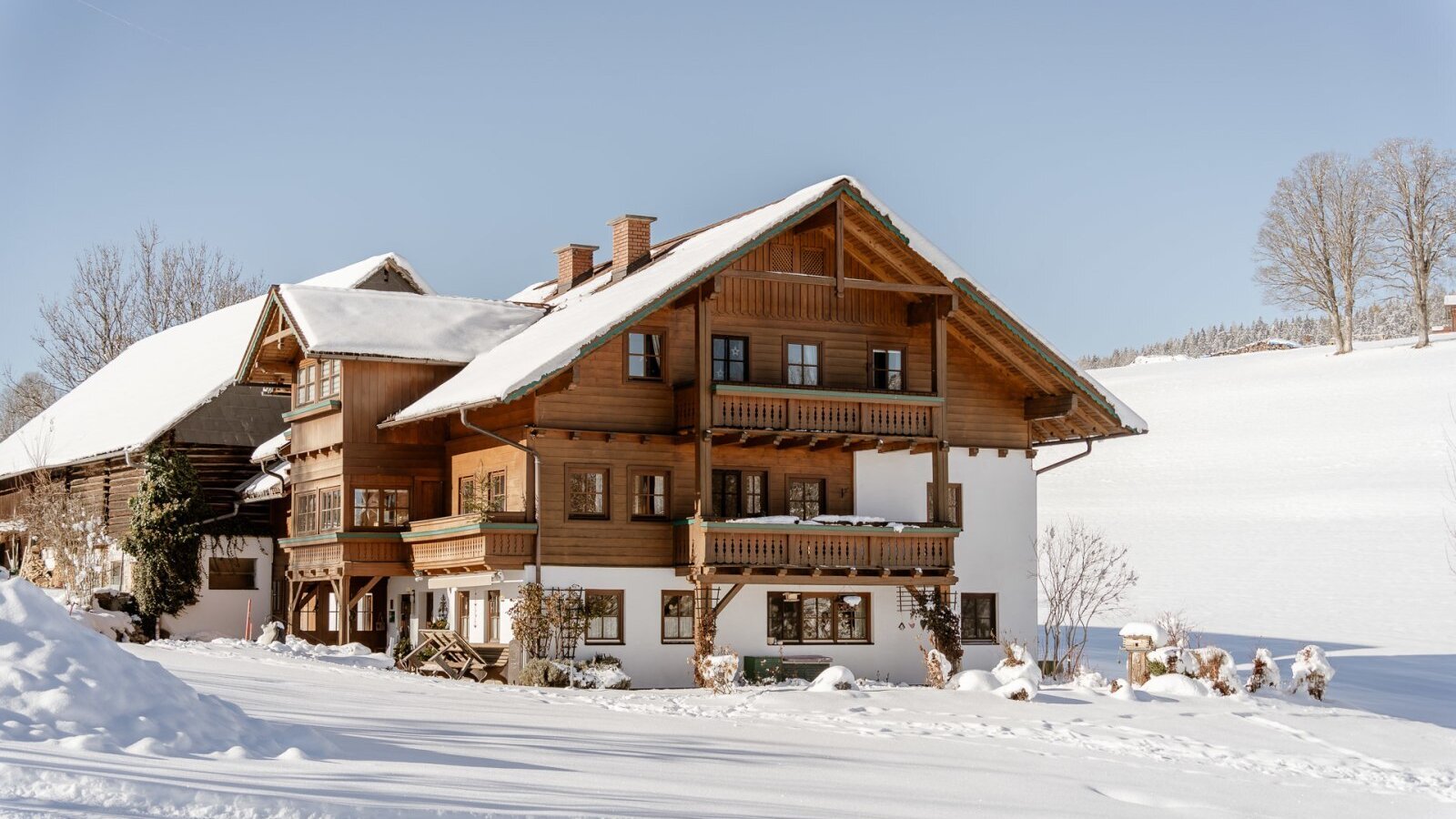 Außenansicht des Bauernhofs im Winter, mit schneebedecktem Dach und Balkonen. (c)Wolfgang Spekner