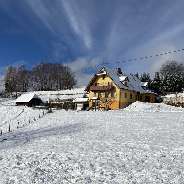 Der Bauernhof im Winter, umgeben von Schnee und mit einem Spielplatz.
