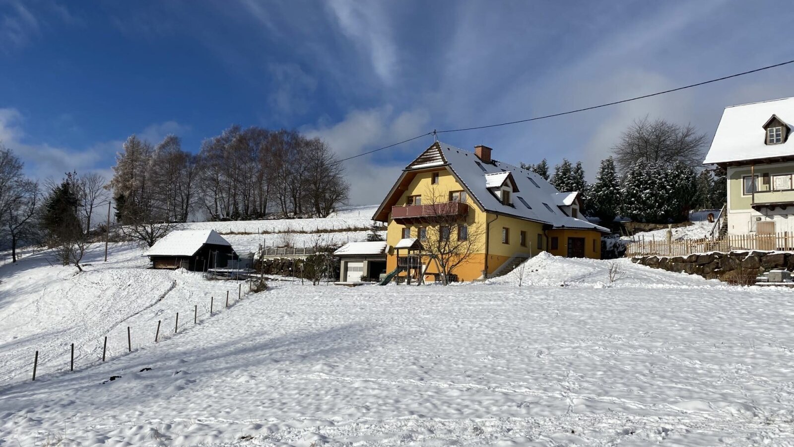 Der Bauernhof im Winter, umgeben von Schnee und mit einem Spielplatz.