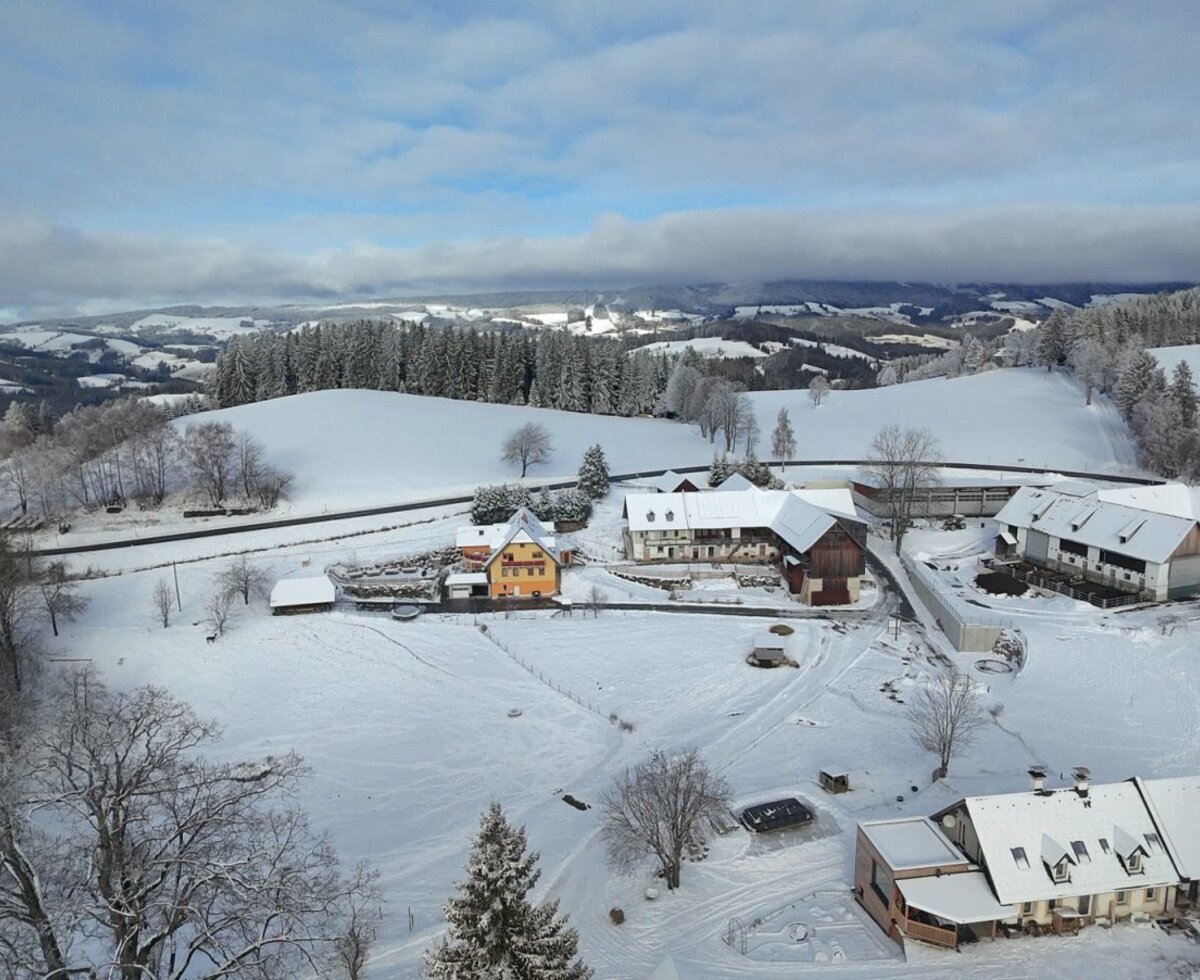 Blick auf den Bauernhof und die schneebedeckte Landschaft des Jogllands im Winter.