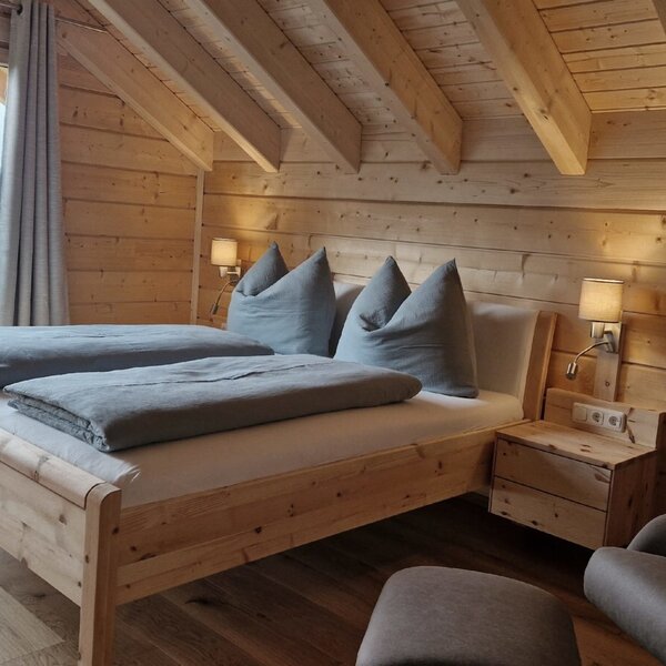 Doppelzimmer im Bauernhof mit Holzwänden, freiliegenden Deckenbalken und einem großen Fenster mit Bergblick.