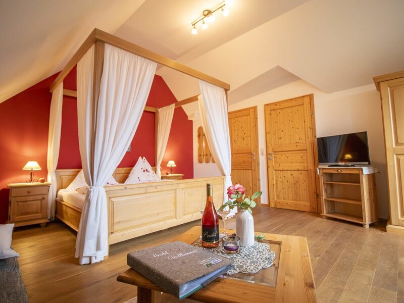 Ein gemütliches Schlafzimmer im Bauernhof mit einem einladenden Himmelbett aus Holz, warmem Licht und Holzmöbeln.