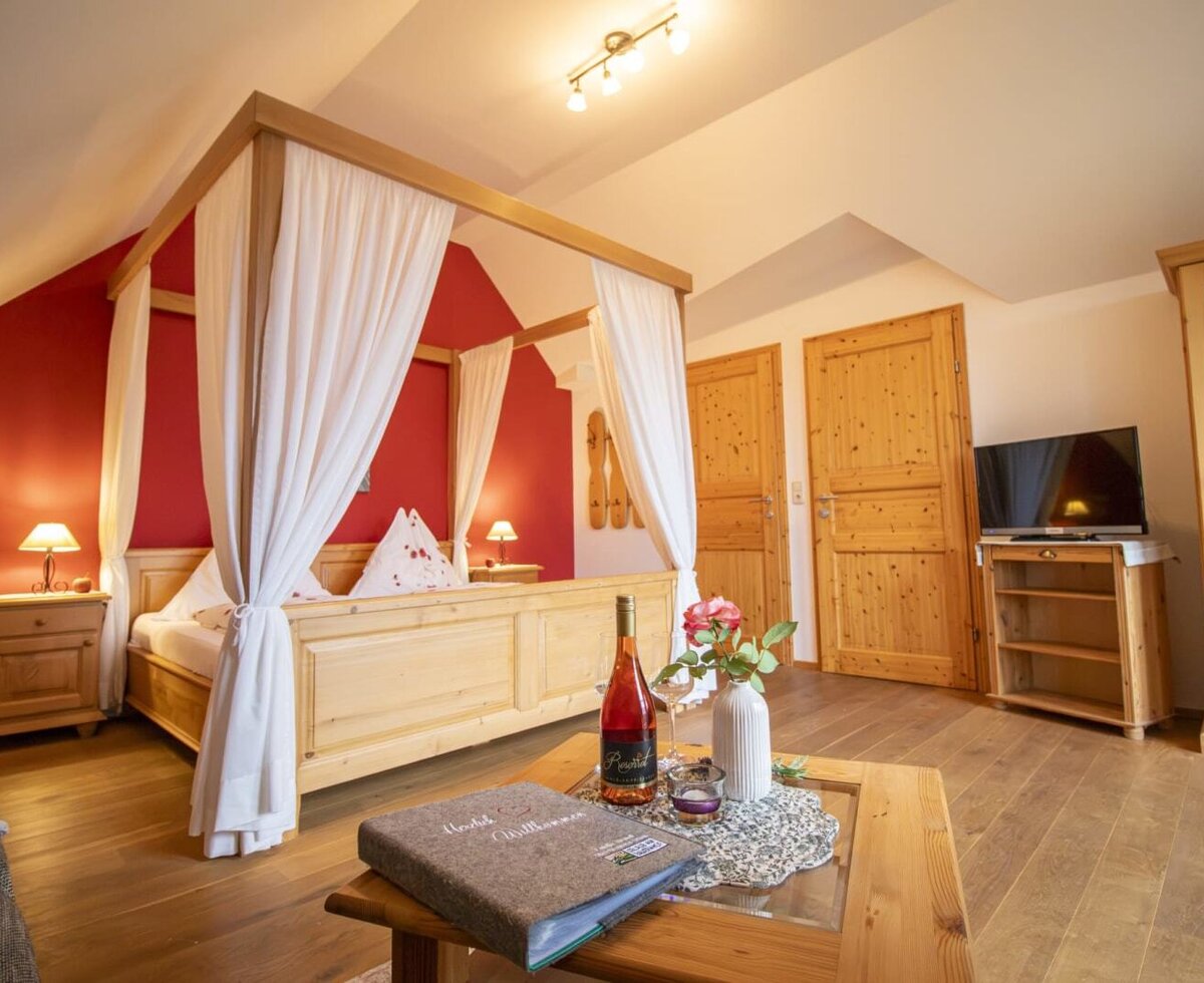 Ein gemütliches Schlafzimmer im Bauernhof mit einem einladenden Himmelbett aus Holz, warmem Licht und Holzmöbeln.