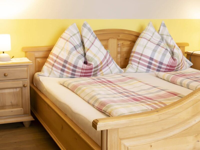 Ein gemütliches Doppelbett aus hellem Holz im Bauernhof