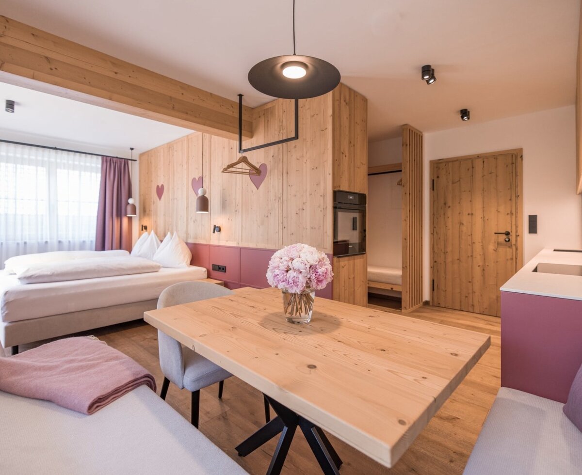 Ein gemütlicher Wohn- und Schlafbereich im Wohnstudio Frieda mit modernen Vollholzmöbeln und einer einladenden Sitzecke.