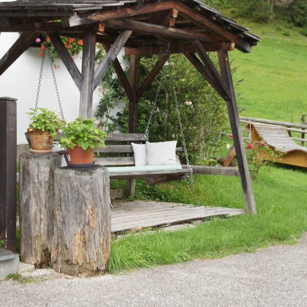 Schaukelbank und Sonnenliege im Gartenbereich des Bauernhofs.
