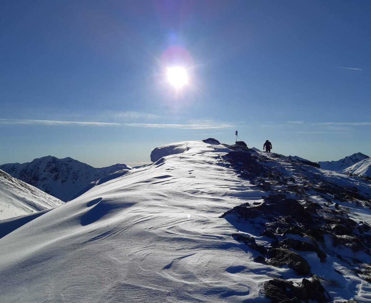 Winterliche Berglandschaft mit einer Person auf einem schneebedeckten Grat, ideal für Wanderungen in der Nähe des Bauernhofs.