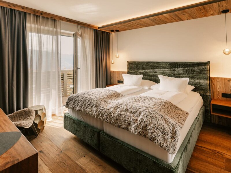 Doppelzimmer im Bauernhof mit Holzboden, Balkonzugang und Holzdetails.
