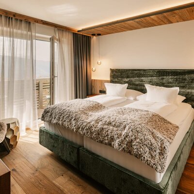 Doppelzimmer im Bauernhof mit Holzboden, Balkonzugang und Holzdetails.