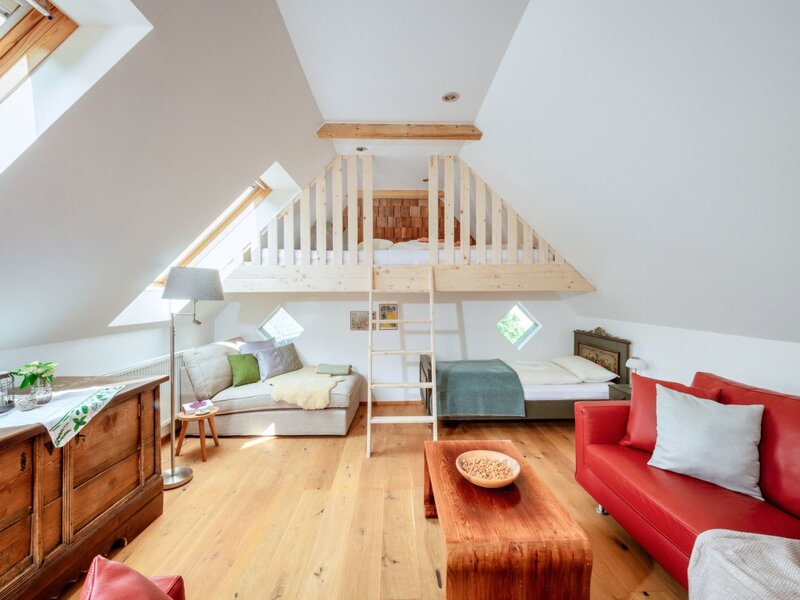 Dachzimmer im Bauernhof mit einem Hochbett, einem Einzelbett und einem Wohnbereich mit zwei Sofas.