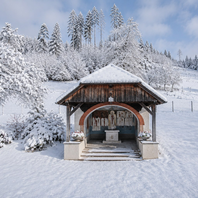 Eine malerische, schneebedeckte Kapelle auf dem Gelände des Bauernhofs inmitten einer idyllischen Winterlandschaft.