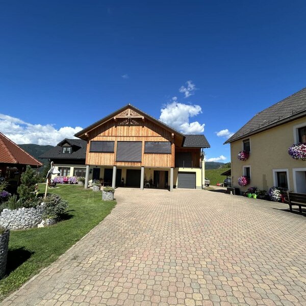 Der Außenbereich des Bauernhofs mit gepflastertem Vorplatz, den verschiedenen Gebäuden und einem Garten mit Pavillon.