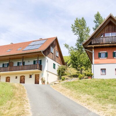 Die beiden Häuser des Anwesens auf einem Hügel, verbunden durch eine Auffahrt, mit Solarpaneelen auf einem Dach und Balkonen.