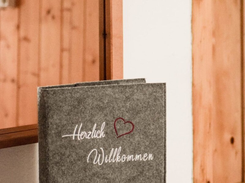 Willkommensbuch für Gäste des Bauernhofs, beschriftet mit 'Herzlich Willkommen' und dem 'Urlaub am Bauernhof' Logo.