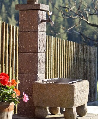 Steinsäule mit Wasserhahn  im Außenbereich des Bauernhofs.