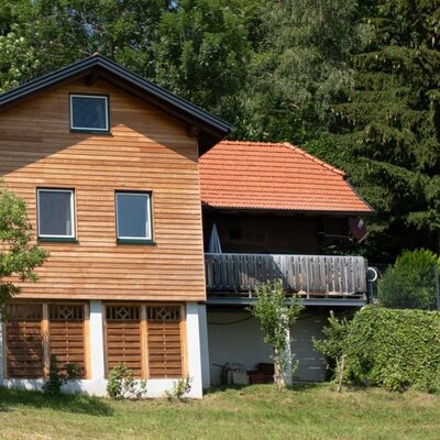 Das einladende Ferienhaus des Bauernhofs mit einer modernen Holzfassade, umgeben von einer grünen Wiese und einem Spielplatz für Kinder.