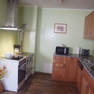 Die Küche im Bauernhof verfügt über einen Holzherd mit Dunstabzugshaube, eine Spüle, eine Mikrowelle und Holzschränke.