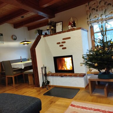 Der Wohnbereich des Bauernhofs bietet einen Kamin mit brennendem Holzfeuer und einen angrenzenden Essbereich.