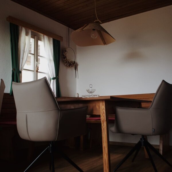 Essbereich mit Holztisch, Stühlen, Eckbank und Fenster.