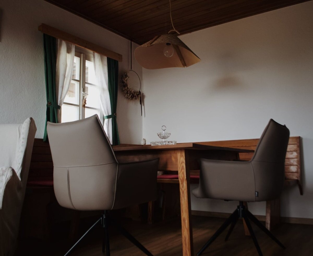 Essbereich mit Holztisch, Stühlen, Eckbank und Fenster.