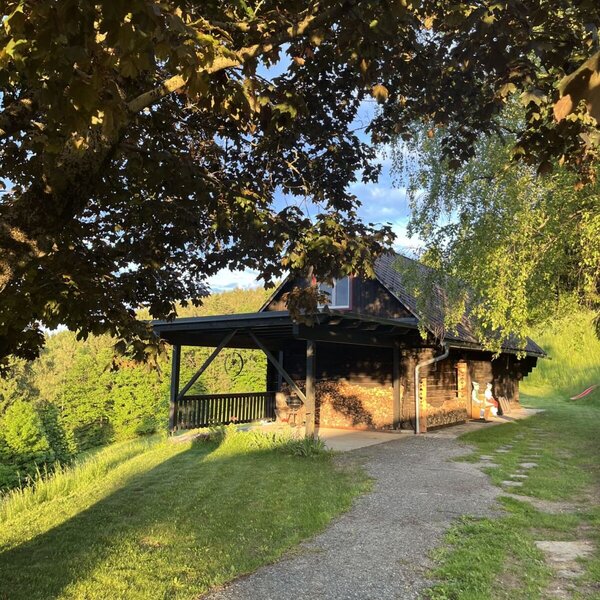 Außenansicht des Ferienhauses mit Holzfassade, überdachter Veranda, mitten im Grünen gelegen