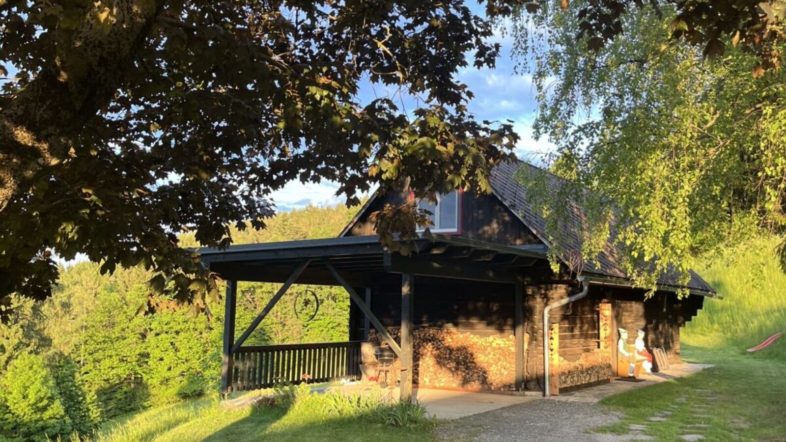 Außenansicht des Ferienhauses mit Holzfassade, überdachter Veranda, mitten im Grünen gelegen