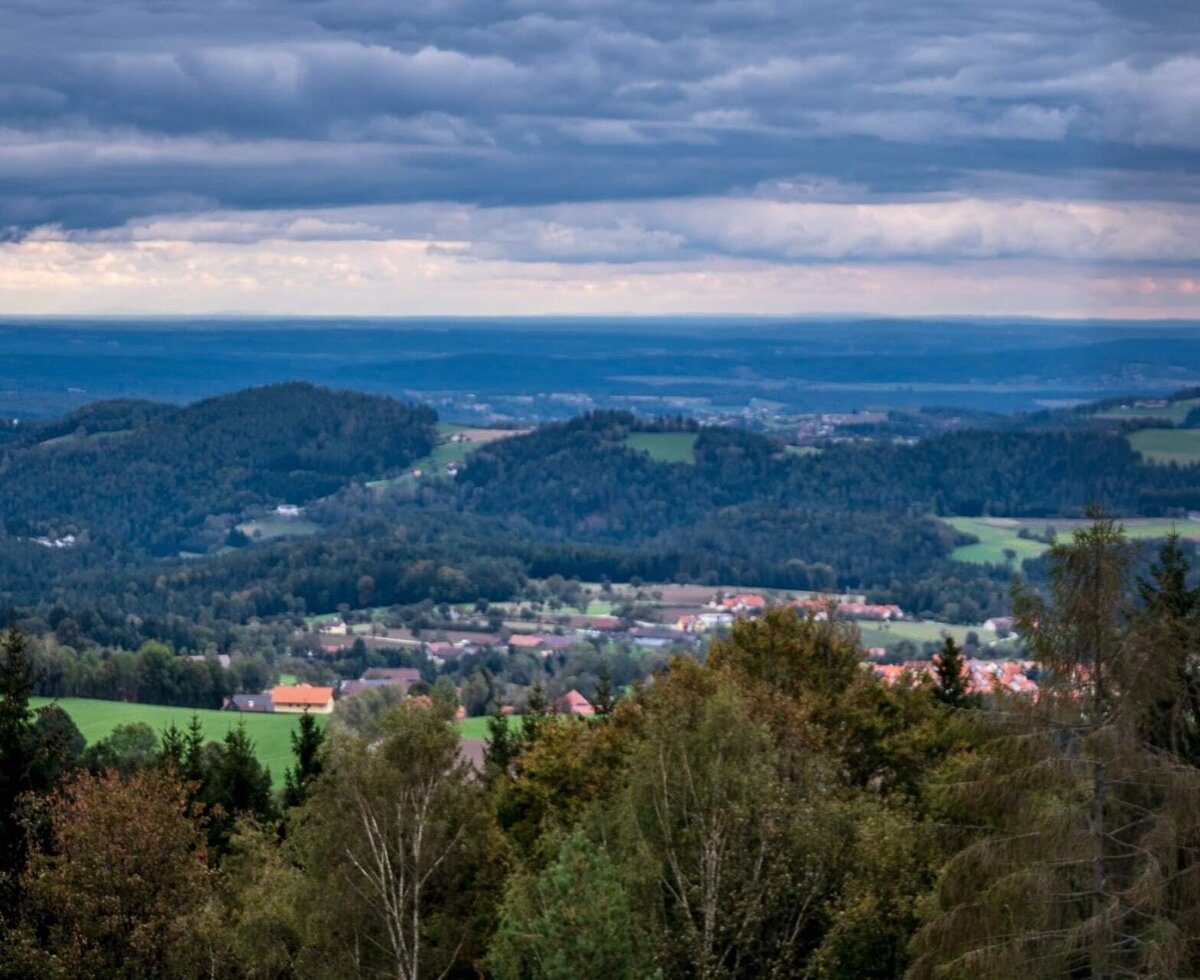 Panoramablick auf die bewaldeten Hügel und ein Dorf unter bewölktem Himmel vom Bed and Breakfast.