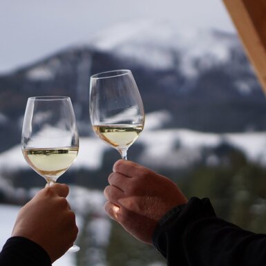 Zwei Weingläser mit Blick auf die verschneite Berglandschaft vom Bauernhof.