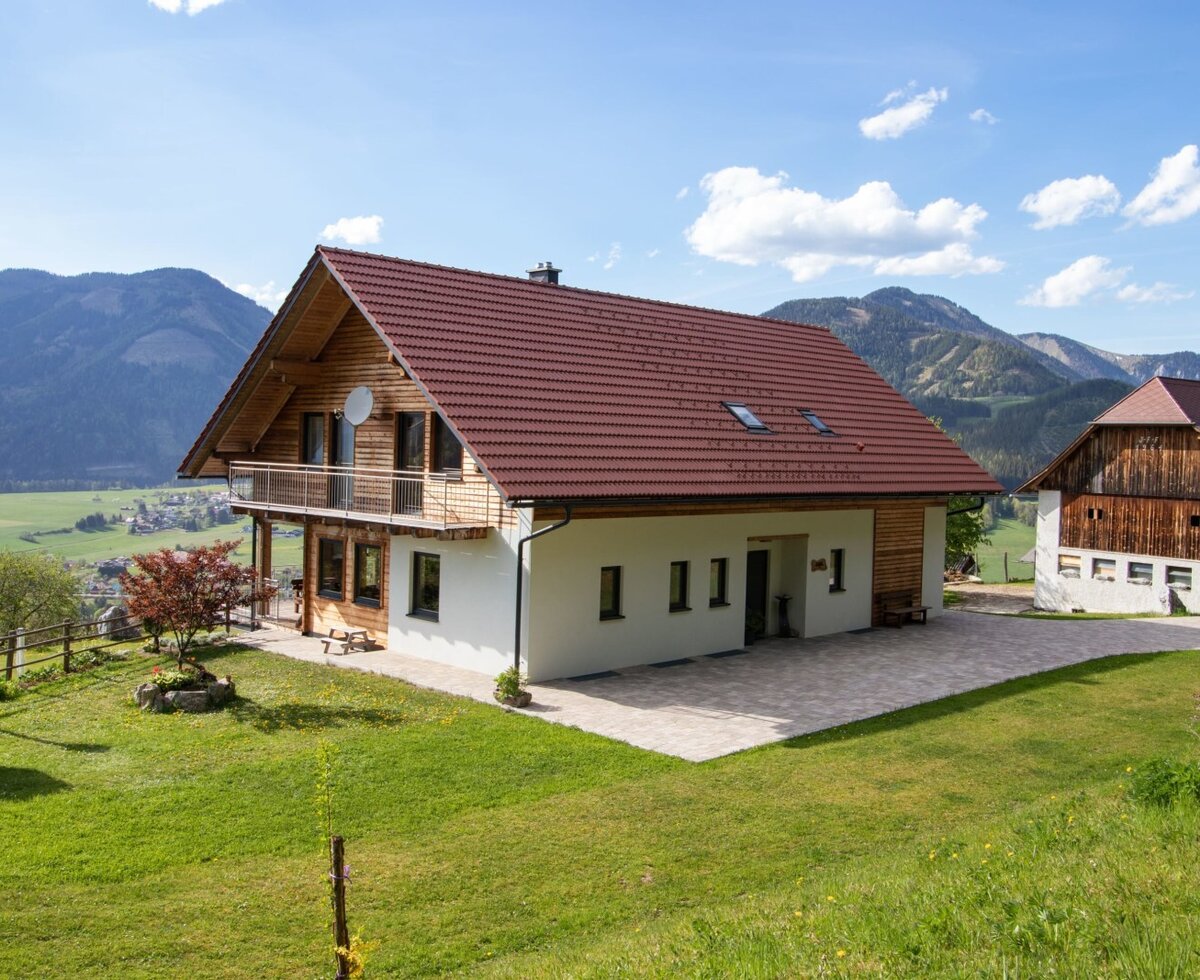 Der Bauernhof mit einem Balkon, einer Terrasse und Blick auf die umliegende Berglandschaft.