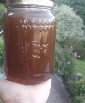 Ein Glas Blütenhonig mit Wabenmuster und Bienenmotiv, erhältlich auf dem Bauernhof.