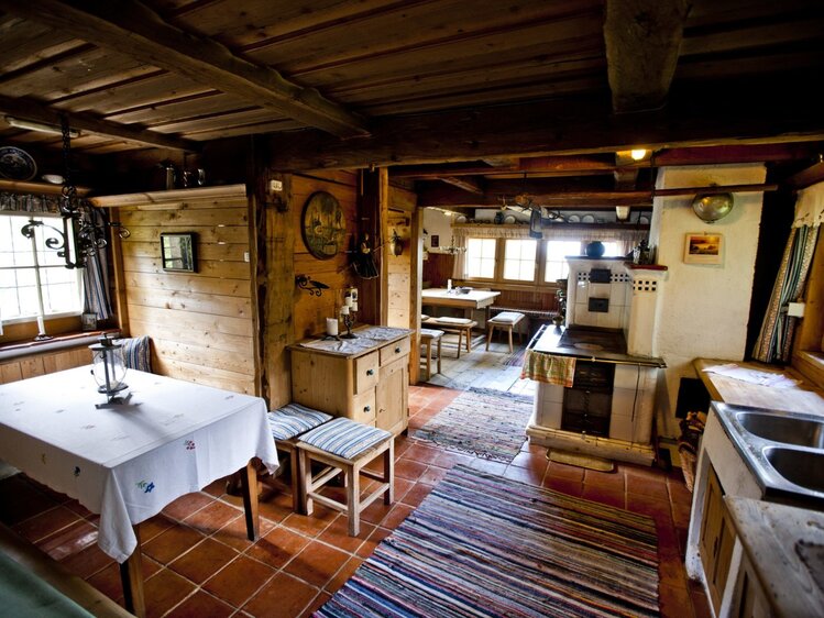 Die Wohnküche des Hofs verfügt über einen Holzherd mit Kachelofen, fließendes Wasser und zwei Sitzecken.