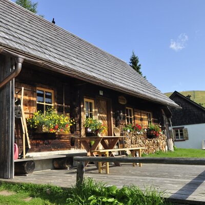 Außenansicht des Hofs mit Holzterrasse, einem Picknicktisch und Blumenkästen an den Fenstern.