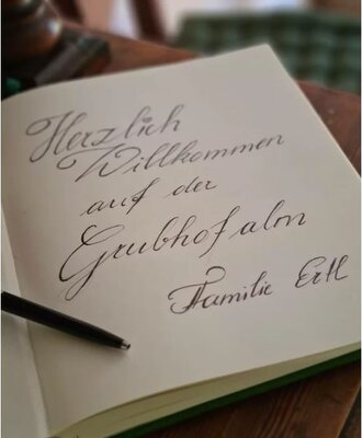 Ein handgeschriebener Willkommensgruß mit "Herzlich Willkommen auf der Grubhofalm Familie Ettl" für die Gäste des Hofes.
