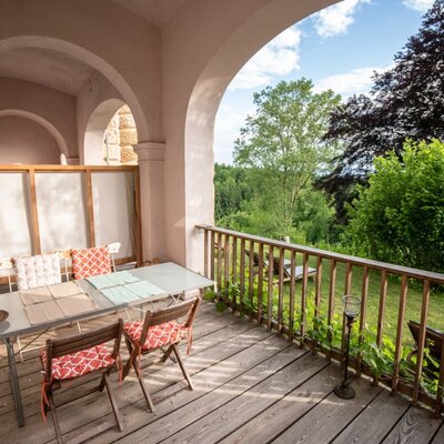 Eine einladende, überdachte Terrasse unter den Arkaden mit einem gemütlichen Sitzbereich und Blick ins Grüne. (c) Stephan Friesinger