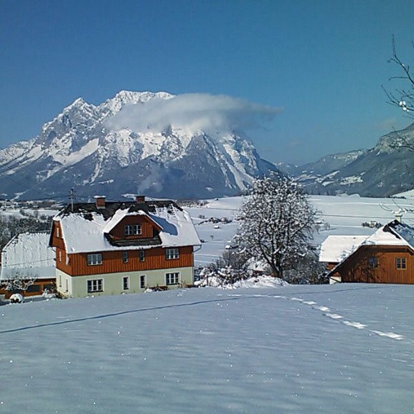 Der schneebedeckte Bauernhof in winterlicher Umgebung mit Blick auf die Berge und das verschneite Tal.