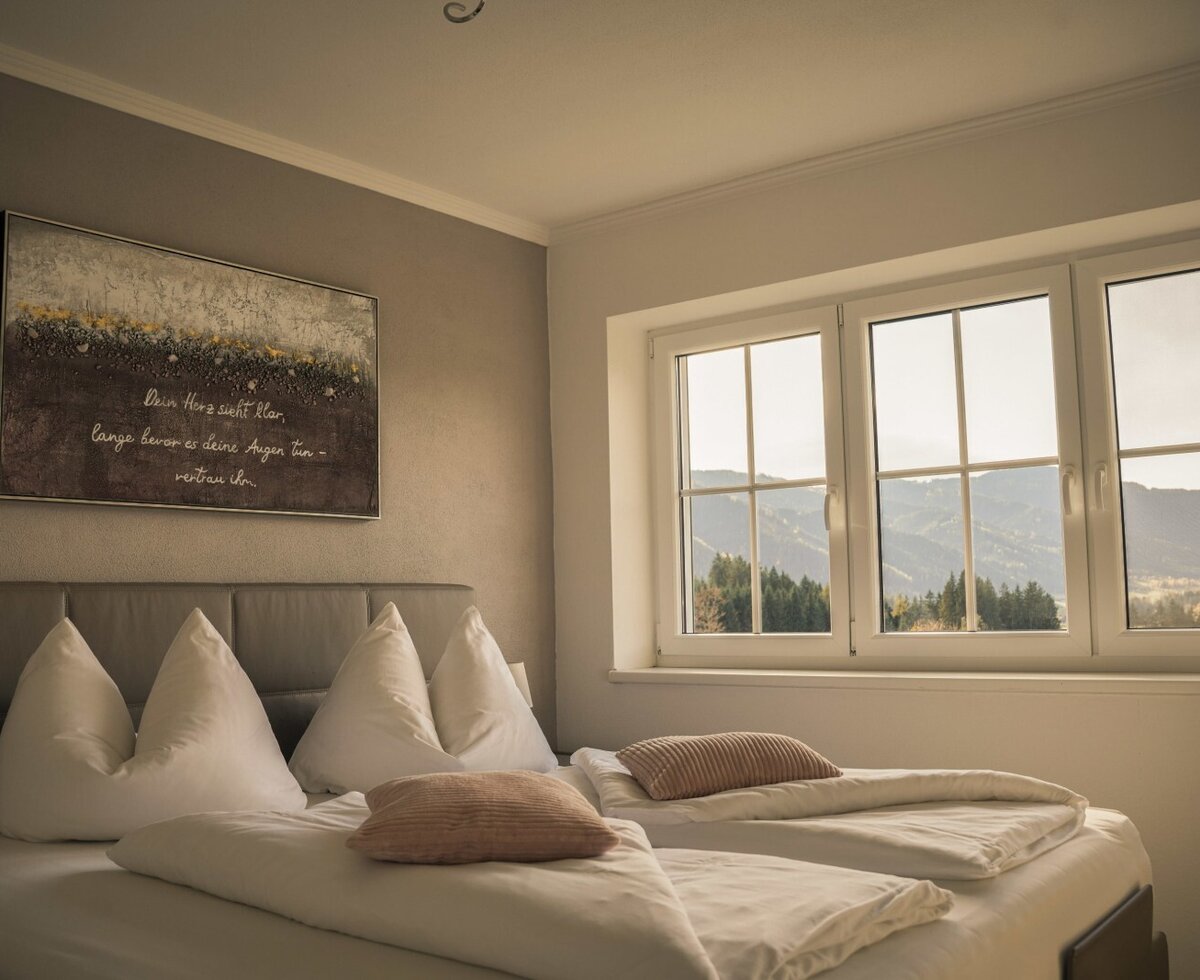 Schlafzimmer mit Doppelbett und Fenster mit Bergblick.