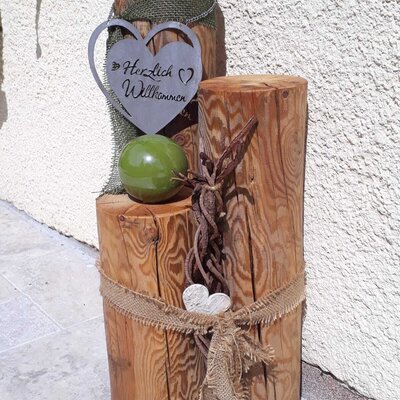 Ein Willkommensschild aus Holz mit der Aufschrift „Herzlich Willkommen“ am Hof.