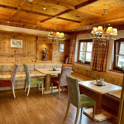 Essbereich des Bauernhofs mit Holztäfelung, gepolsterten Eckbänken und Tischen.