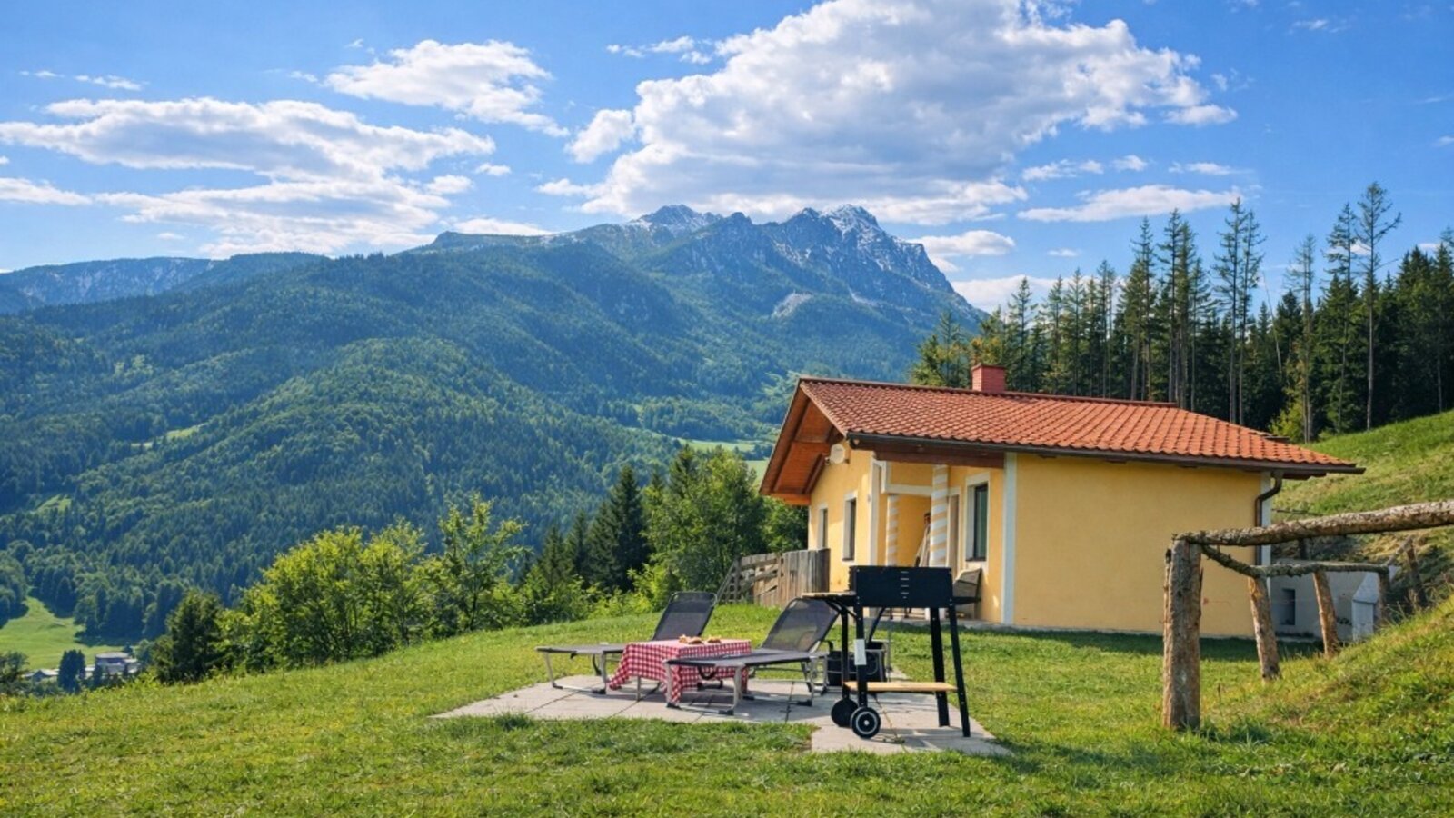 Außenbereich des Bed and Breakfast mit Terrasse, Grill, Liegestühlen und Bergblick.