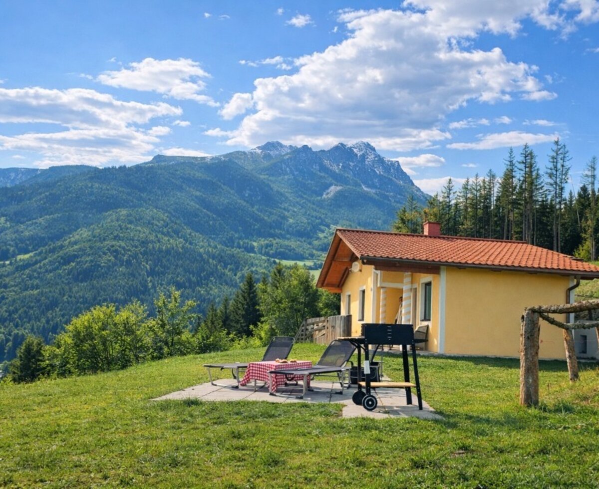 Außenbereich des Bed and Breakfast mit Terrasse, Grill, Liegestühlen und Bergblick.