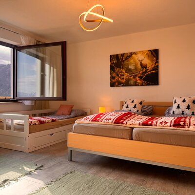 Schlafzimmer im Bed and Breakfast mit Doppelbett, zusätzlichem Einzelbett und Bergblick aus dem Fenster.