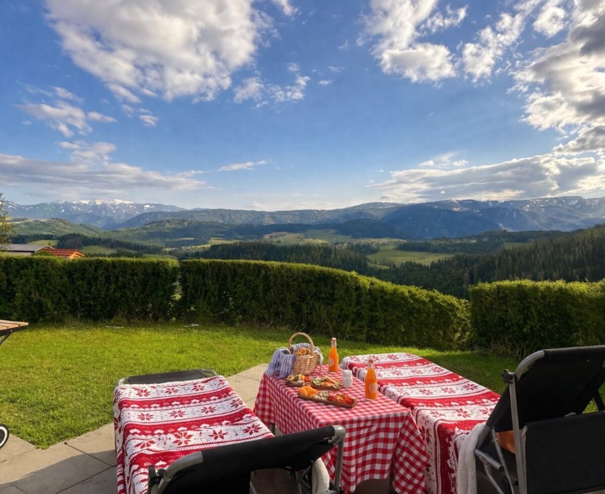 Terrasse des Bed and Breakfast mit einem gedeckten Tisch, Liegestühlen und Grill, mit Panoramablick auf Berge und Täler.
