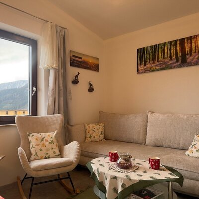 Der Wohnbereich des Bed and Breakfast mit Sofa, Schaukelstuhl und Blick auf die Berge.
