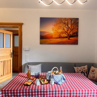 Der Frühstücksbereich des Bed and Breakfast mit einem gedeckten Tisch, rot-weiß karierter Tischdecke und einer Eckbank.