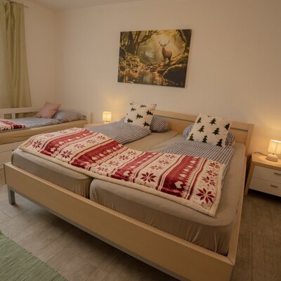 Schlafzimmer im Bed and Breakfast mit Doppelbett, Einzelbett, Nachttisch und Fenster.