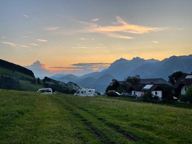 Blick auf die umliegende Berglandschaft und grüne Wiesen bei Sonnenuntergang vom Ferienhaus.