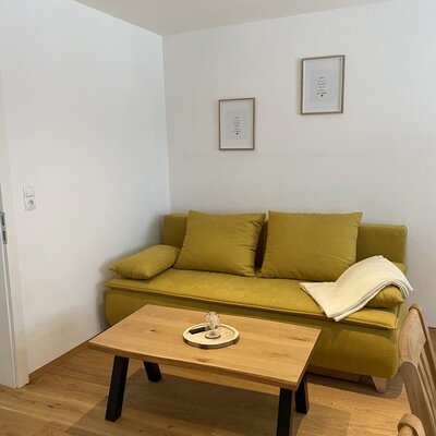 Grüngelbe Couch mit zwei Polstern  und einer hellgelben Decke
