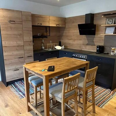 Küche mit kleinem Esstisch aus Holz und vier Hockern