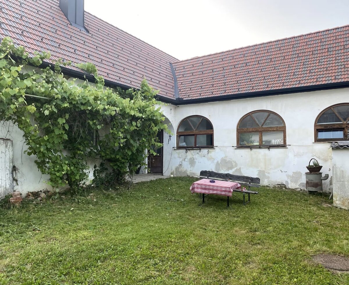Noch nicht vollständig renovierter Innenhof des alten, revitalisierten Hauses mit Wiese und Gartengarnitur.
